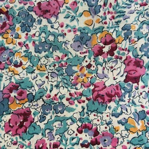 May include: A fabric featuring a dense floral pattern on an off-white background. The design consists of small, clustered flowers in shades of magenta, teal, light blue, and yellow, creating a continuous, intricate botanical print across the surface.