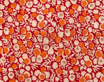 May include: Red fabric with a white and orange floral pattern.