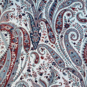 Puede incluir: Una tela blanca con un patrón paisley en tonos rojos y azules. El patrón presenta intrincados remolinos y motivos florales.