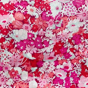 May include: A pink and white floral fabric with a repeating pattern of small and large flowers. The fabric has a vintage feel and would be perfect for a variety of projects.