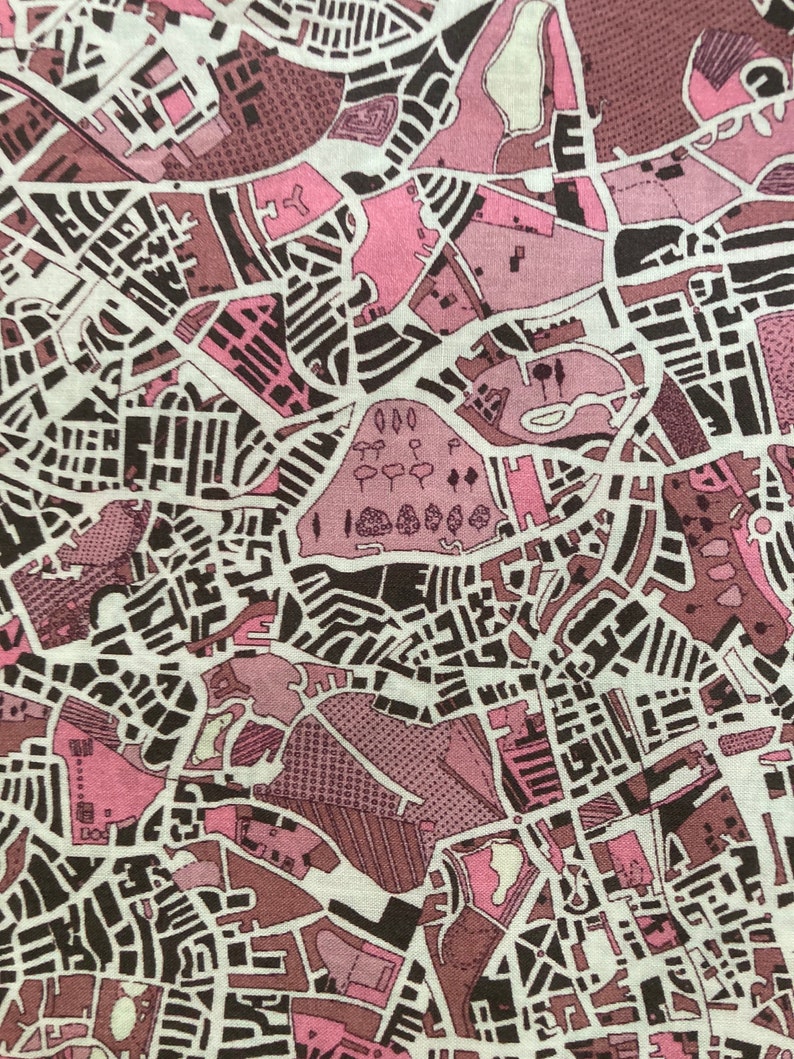 Op de afbeelding: Een roze en bruine stof met een kaart-achtig ontwerp. De stof heeft een verscheidenheid aan vormen en lijnen, waardoor een complex en ingewikkeld patroon ontstaat.