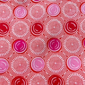 May include: A fabric textile featuring a repeating geometric pattern of red concentric circles and radiating lines interspersed with solid pink and magenta circles of varying shades, creating a dense, vibrant, and symmetrical graphic design.
