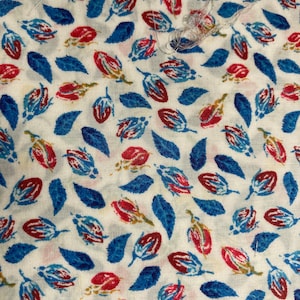 May include: White fabric with a repeating pattern of blue and red stylised flower buds and leaves.
