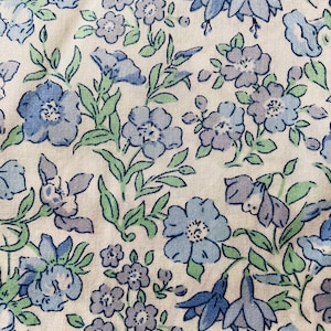 May include: A white fabric with a blue and green floral pattern. The pattern features small and large flowers, leaves, and stems.