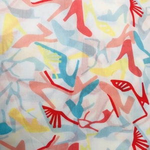 May include: A white fabric with a repeating pattern of colorful high-heeled shoes. The shoes are in shades of red, pink, blue, and yellow.