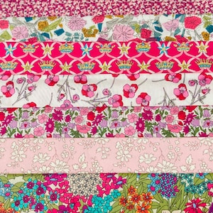 Puede incluir: Una colección de telas Liberty con diseños florales y estampados coloridos en tonos rosa, verde y azul. Las telas están dispuestas en tiras horizontales, con una caja de madera con la inscripción "LIBERTY FABRICS" en la parte superior.
