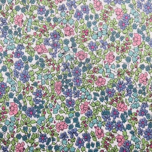 Könnte beinhalten: Ein weißer Stoff mit einem sich wiederholenden Muster aus kleinen rosa, blauen und grünen Blumen. Die Blumen sind in einem zufälligen Muster angeordnet und von kleinen grünen Blättern umgeben.