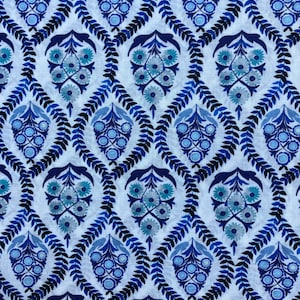 Op de afbeelding: Een witte stof met een herhalend patroon van blauwe bloemenmotieven. De bloemenmotieven worden omringd door een blauwe bladrand.