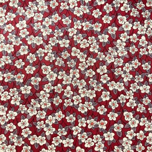 Puede incluir: Tela roja con un patrón floral blanco. Las flores son pequeñas y tienen un diseño simple. La tela es perfecta para proyectos de manualidades, acolchado o confección de ropa.