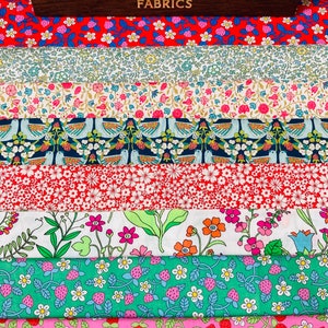 May include: A stack of colourful fabric swatches with floral and bird patterns. The fabric is from Liberty Fabrics.