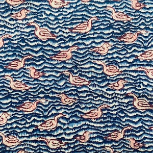 Puede incluir: Un patrón repetido de cisnes estilizados sobre un fondo de agua ondulada. Los cisnes son de color rosa con contornos marrones, sobre un fondo azul oscuro. El agua tiene un aspecto texturizado y dibujado a mano.