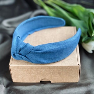 Peut inclure: Un bandeau en tissu bleu avec un nœud. Le bandeau est sur une boîte brune.