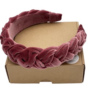 Peut inclure: Un serre-t&ecirc;te en velours rose avec un design tress&eacute;. Le serre-t&ecirc;te est sur une bo&icirc;te brune avec le texte "ACCESSORIES & MORE" sur un autocollant blanc.