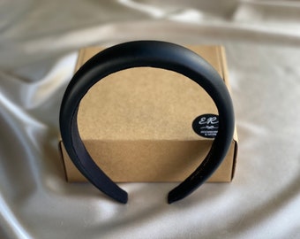 May include: A black padded headband. The headband is on a brown box with a black and white sticker that says "E&R ACCESSORIES & MORE".