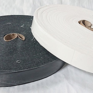 May include: Two rolls of fabric tape, one black and one white. The rolls are wound tightly and are ready to be used for sewing or crafting projects.