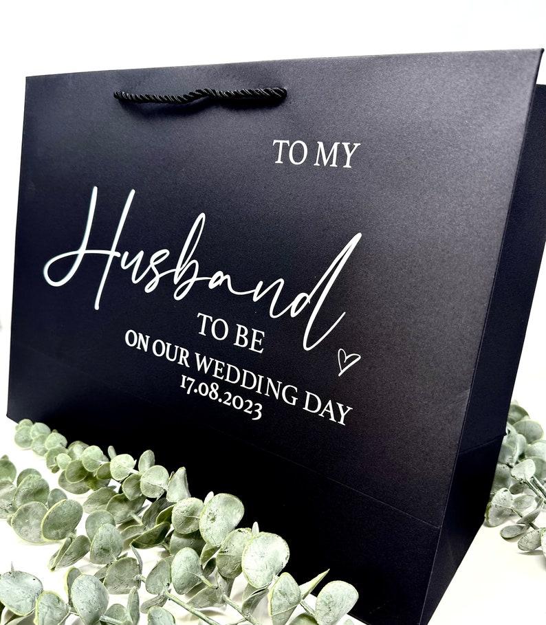 Puede incluir: Bolsa de regalo negra con texto blanco que dice "To my Husband to be on our wedding day 17.08.2023".