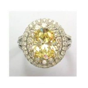 May include: A yellow oval-shaped diamond ring with a double halo of smaller diamonds set in a white gold band.