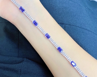 May include: A silver bracelet with a double row of clear cubic zirconia stones and blue rectangular gemstones.