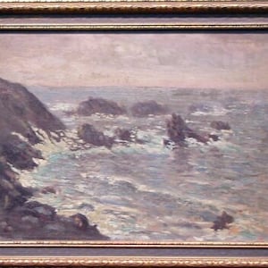 May include: A painting depicting a seascape with a rocky coastline and choppy waves. The sky is a soft, pale pink and the water is a cool, blue-grey. The painting is framed in a gold frame.