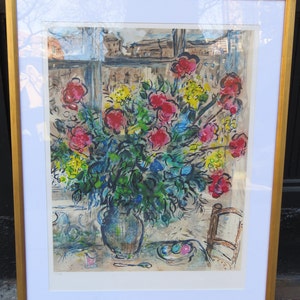 Pode incluir: Uma impressão emoldurada de uma pintura que mostra um vaso de flores coloridas em um quarto com uma janela. As flores são vermelhas, rosas, amarelas e azuis. O vaso é marrom e tem um padrão de grade. Há uma cadeira no fundo.