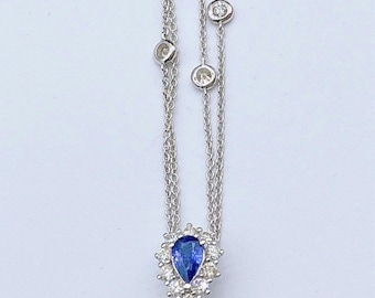 May include: A silver necklace with a pendant featuring a large green opal surrounded by smaller blue and green gemstones. The necklace has a delicate chain with small diamonds.