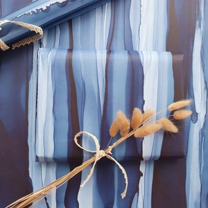 May include: Blue and white abstract patterned wrapping paper with a brown ribbon and dried flowers.