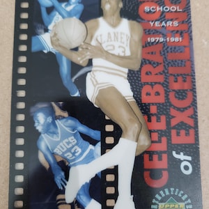 Peut inclure: Une carte de collection de basket-ball représentant une photo en noir et blanc d'un joueur de basket-ball portant un maillot blanc avec le numéro 23 et le mot "CLANEY" sur le devant. La carte a une bordure rouge, blanche et noire avec le texte "CELEBRATION of EXCELLENCE" et "HIGH SCHOOL YEARS 1979-1981". La carte est de Upper Deck Collectibles.
