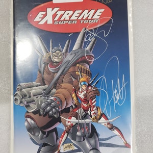 以下が含まれることがあります： 未来的なロボットと弓矢を持った人間のキャラクターが描かれたコミックの表紙。表紙には、T. Nanci、J. Daly、J.T. Krulの3人のアーティストのサインがある。コミックのタイトルは「EXTREME SUPER TOUR」で、表紙には「AUTOGRAPHED」とラベルが貼られている。