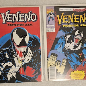 Puede incluir: Dos cómics con Venom. Las portadas muestran a Venom en negro, blanco y azul, con el título "Veneno" y "Protector Letal". El primer cómic es el número 1, y el segundo es el número 2. El logotipo de Marvel Comics es visible.