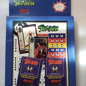 May include: A blue and white box containing a Spawn Power Cardz game. The box features a Spawn character illustration and includes two 50-card starter decks. The text on the box reads "Spawn TM and © 1995 TMP Inc., PowerCardz TM and © 1995 Skyverse."