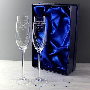 Può includere: Due flûte da champagne in vetro trasparente con steli lunghi, ciascuna con un design a cuore inciso, un piccolo cristallo incastonato e il testo inciso Congratulations Mr & Mrs Wright 09.12.18 Weston Hall xxx, in una scatola blu satinata.