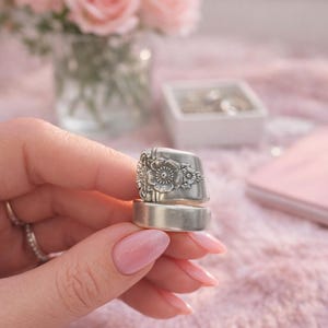 May include: A white ceramic mug with a black handle and the text "But First, Coffee" in a black, handwritten-style font. The mug is on a white surface.