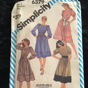 May include: Simplicity sewing pattern number 6379 for a dress. The pattern is adjustable for miss petite and includes three different styles. The pattern is printed on a white background with blue and white stripes.