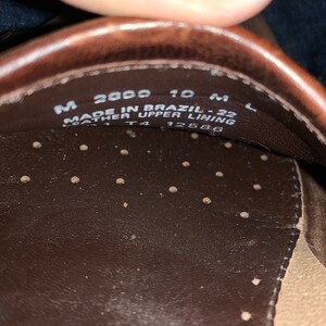 Peut inclure: Gros plan de l'int&eacute;rieur d'une chaussure en cuir marron. La chaussure est &eacute;tiquet&eacute;e "Made in Brazil - 22 Leather Upper Lining" et porte la taille "M 2000 10 M L" et "T4 12586" imprim&eacute;s sur la semelle int&eacute;rieure.