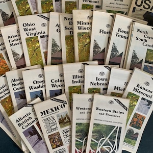 May include: A collection of vintage AAA travel maps, featuring various states and provinces. The maps have a white background with colorful illustrations and text, including "New York," "Mexico," and "Western States." The maps are from the American Automobile Association.