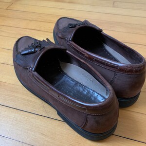 Peut inclure: Une paire de mocassins &agrave; franges en cuir marron avec une semelle en caoutchouc noir. Les mocassins ont une doublure en cuir marron et une semelle int&eacute;rieure blanche avec le mot "Rockport" imprim&eacute; dessus.