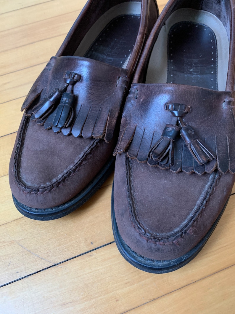 Peut inclure: Une paire de mocassins &agrave; franges en cuir marron avec une semelle marron fonc&eacute;. Les mocassins ont un d&eacute;tail de frange sur le devant et sont us&eacute;s.