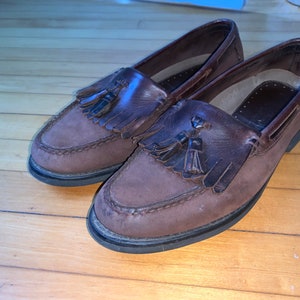 Peut inclure: Une paire de mocassins en cuir marron &agrave; glands avec une semelle marron fonc&eacute;.