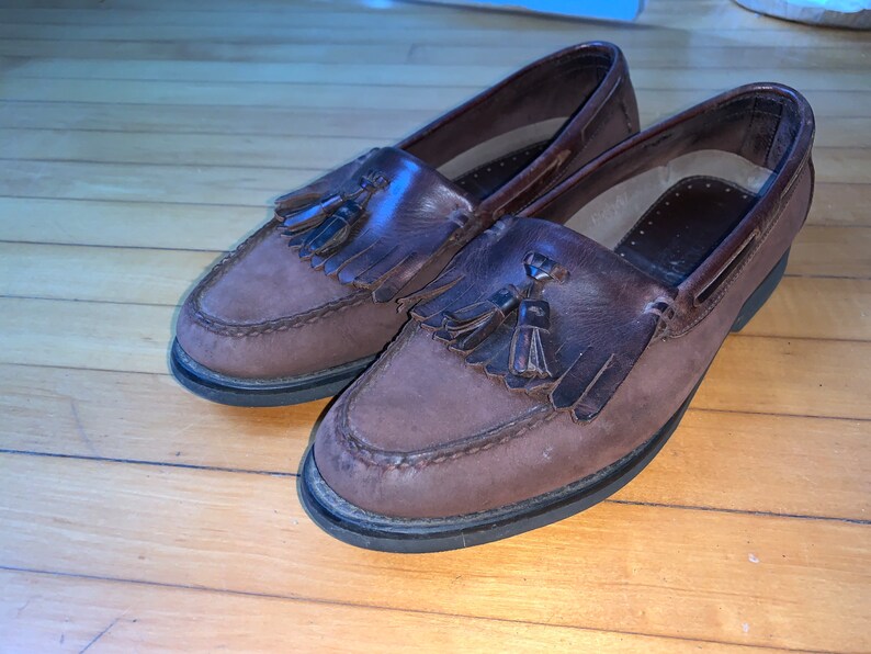 Peut inclure: Une paire de mocassins en cuir marron &agrave; glands avec une semelle marron fonc&eacute;.