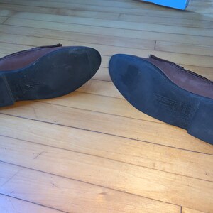 Peut inclure: Une paire de mocassins en cuir marron avec des semelles en caoutchouc noir. Les semelles ont un motif textur&eacute;.