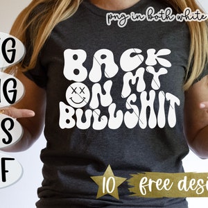 May include: A gray t-shirt with white text that reads "Back on my Bullshit" in a retro font. The text is surrounded by a white smiley face with two X's for eyes. The text "10 free designs" is also visible on the shirt.