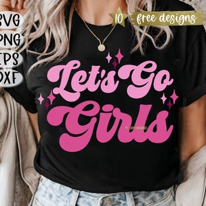 May include: A black t-shirt with a pink and white graphic that says "Let's Go Girls" in a retro font. The graphic is surrounded by small pink stars.