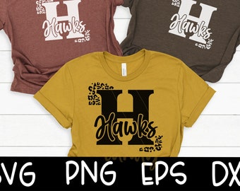 Könnte beinhalten: Ein gelbes T-Shirt mit einem schwarzen Buchstaben H und dem Wort "Hawks" in schwarzer Schrift. Der Buchstabe H ist von einem Leopardenmuster umgeben.