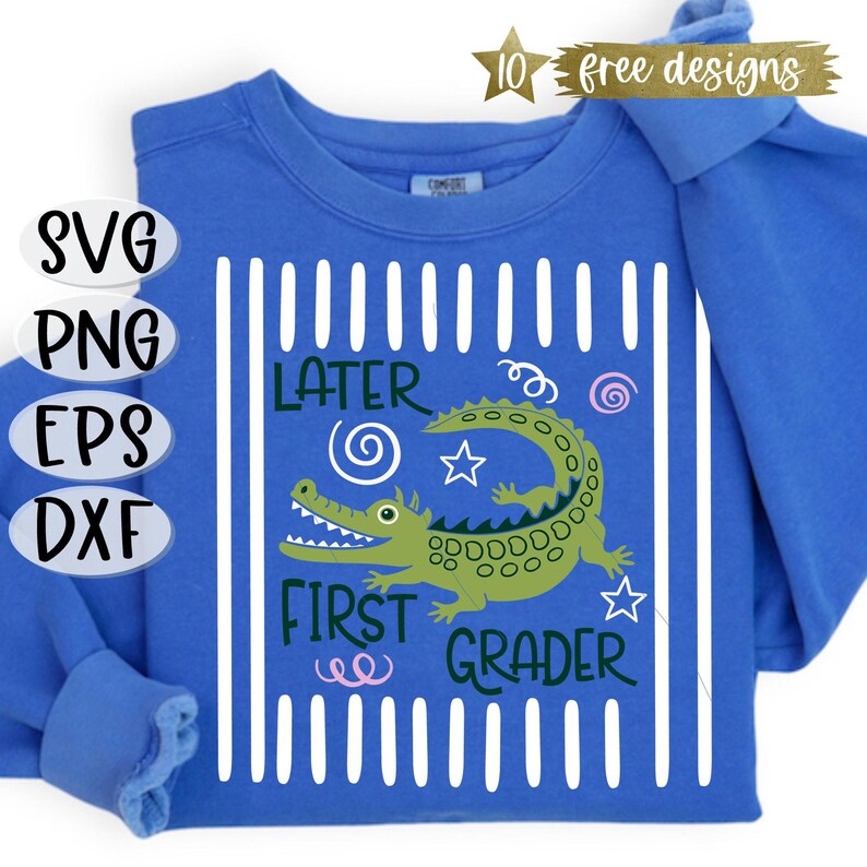 May include: A blue long-sleeve shirt with a green alligator graphic and the words "Later First Grader." The design includes white vertical stripes and decorative swirls and stars. The shirt also has the text "10 free designs."