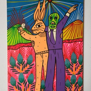 May include: Colorful folk art painting featuring two figures: an orange rabbit-like character and a person in a green mask and purple suit. The background includes mountains, a blue sky with radiating lines, and a pink floral pattern. The artist's name, JESUS LORENZO, is at the bottom.