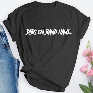 May include: Black t-shirt with white text that reads "DIBS ON BAND NAME" in a stylized font.