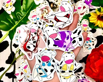 May include: A collection of cow-themed stickers featuring various designs. The stickers are black and white with colorful accents and feature cows wearing lingerie and other playful outfits.