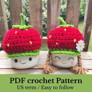 May include: PDF crochet pattern for two strawberry-themed mug cozies. The cozies are red and green with a white daisy on one. The pattern is written in US terms and is easy to follow.