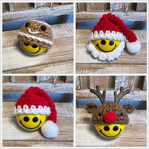 May include: Four crocheted ornaments with smiley faces. The ornaments are wearing different hats, including a Santa hat, a reindeer hat, a gingerbread man hat, and a brown hat with white trim.