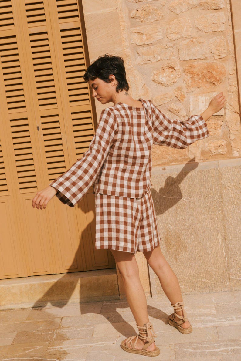 K&ouml;nnte beinhalten: Eine Frau tr&auml;gt ein braunes und wei&szlig;es Gingham-Karo-Oberteil und passende Shorts. Sie tr&auml;gt braune Sandalen mit Schn&uuml;rsenkeln.